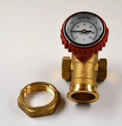 Remko-Temperaturregelventil mit Manometer, goldfarbener Messingkörper und rotem Drehknopf. Eine Messingmutter liegt daneben.