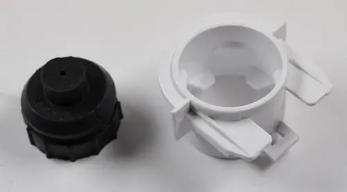 Zwei separate Teile eines Verdampferlagers. Links ein schwarzes Kunststoffteil mit Gewinde und rechts eine weiße Halterung mit seitlichen Ausstanzungen. Von der Marke Remko.