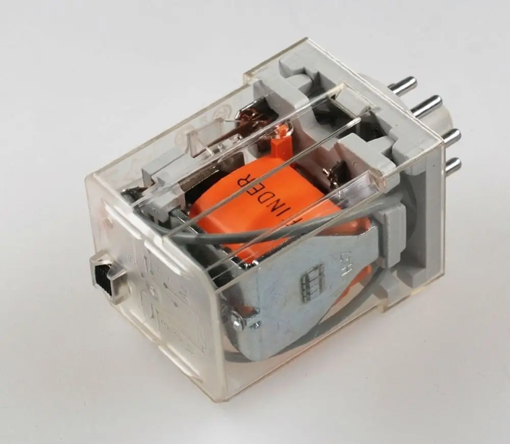 Transparente Gehäuse mit orangefarbener Spule und Metallmechanismus, vermutlich von der Marke Remko. Gerät mit elektrischen Anschlüssen zur Überwachung.