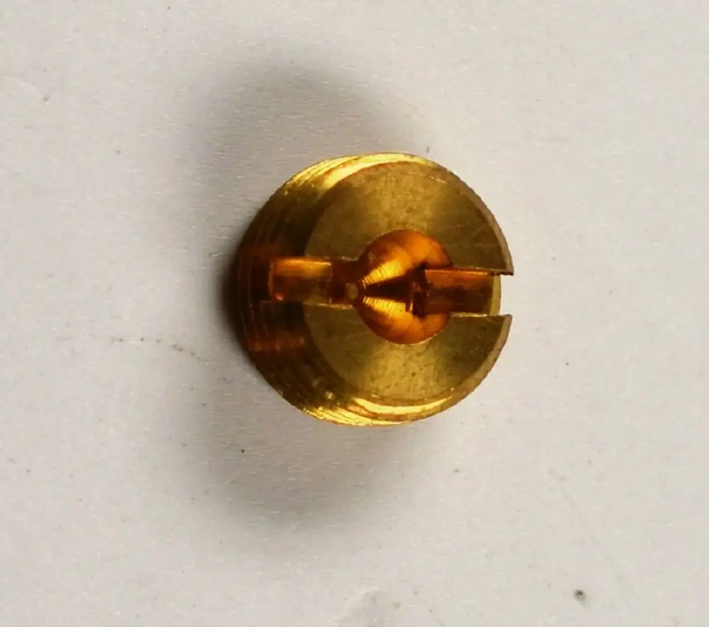 Zündgasdüse von Remko, goldfarbener metallischer Körper mit einem zentralen Kanal und einer runden Öffnung, auf flacher Oberfläche abgebildet.