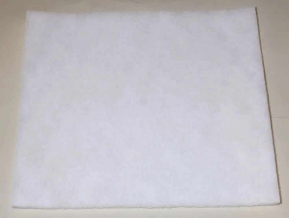 Weißes Filtermaterial auf einer flachen Oberfläche, möglicherweise ein Staubfilter von Remko. Die Struktur ist durch kleine Fasern erkennbar.