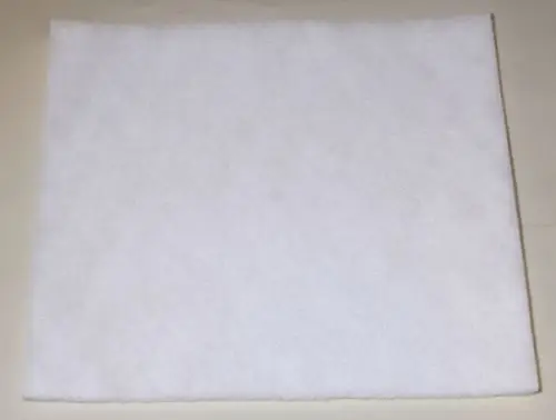 Weißes Filtermaterial auf einer flachen Oberfläche, möglicherweise ein Staubfilter von Remko. Die Struktur ist durch kleine Fasern erkennbar.