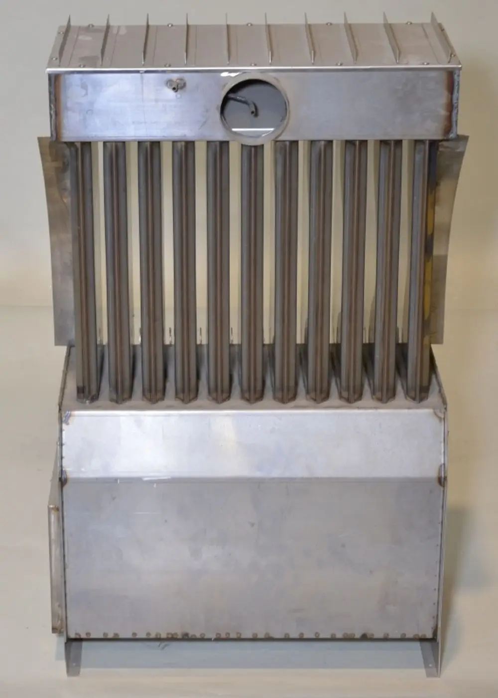 Wärmetauscher aus Metall mit vertikalen Röhren und einer Öffnung an der Oberseite, hergestellt von Remko. Gerät mit funktionalem Design für den Wärmeaustausch.
