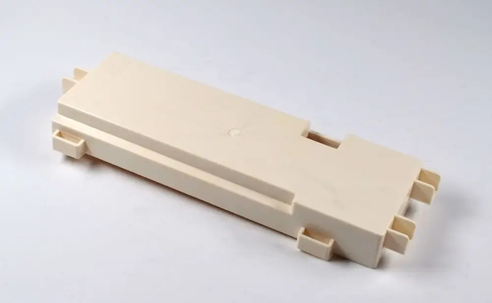 Weißes Plastikteile, rechteckig mit seitlichen Halterungen, möglicherweise ein Gehäuse von Remko für elektronische Komponenten oder Platinen.