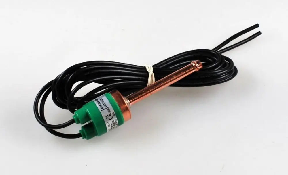 Niederdruckwächter mit einem grünen Anschlussstück und einem metallischen Sensor, umgeben von schwarzem Kabel. Hergestellt von Remko.