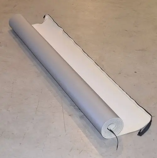 Gerollte Isolierung von Remko, mit einer grauen Oberseite und einer weißen Unterseite, auf einem neutralen Untergrund aus Beton.