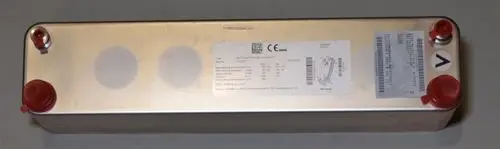 Wärmetauscher von Remko, rechteckige Metallkonstruktion mit zwei rotem Anschlusssockel, diverse technische Daten auf einem Aufkleber, auf einer neutralen Fläche platziert.