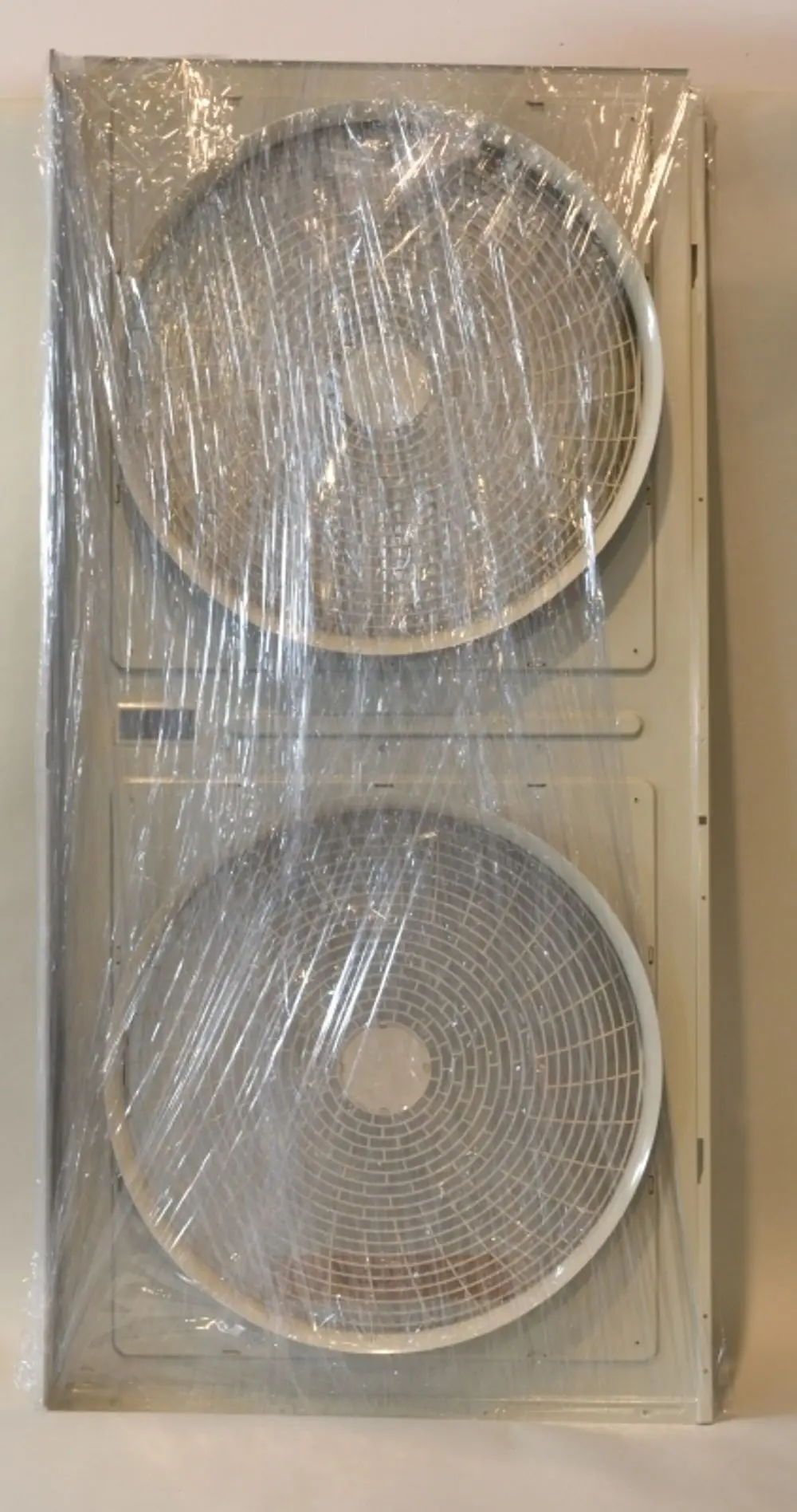 Zwei Ventilatoren hinter Klarsichtfolie, montiert auf einer Halterung. Zu erkennen sind die Gitterstrukturen der Ventilatoren. Hersteller ist Remko.