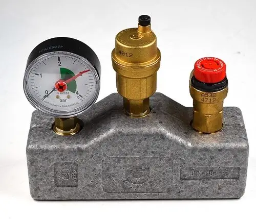 Sicherheitsbaugruppe von Remko mit Manometer und zwei Ventilen, montiert auf einem grauen Block aus Schaumstoff. Zeigt den Druck in bar an.