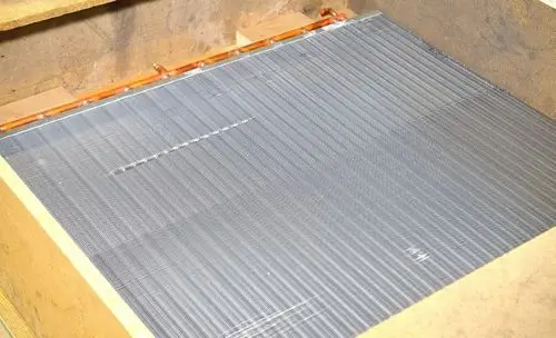 Remko Lamellenverflüssiger in rechteckiger Form, bestehend aus mehreren parallel angeordneten Lamellen auf einer flachen Oberfläche, montiert in einer holzverkleideten Umgebung.
