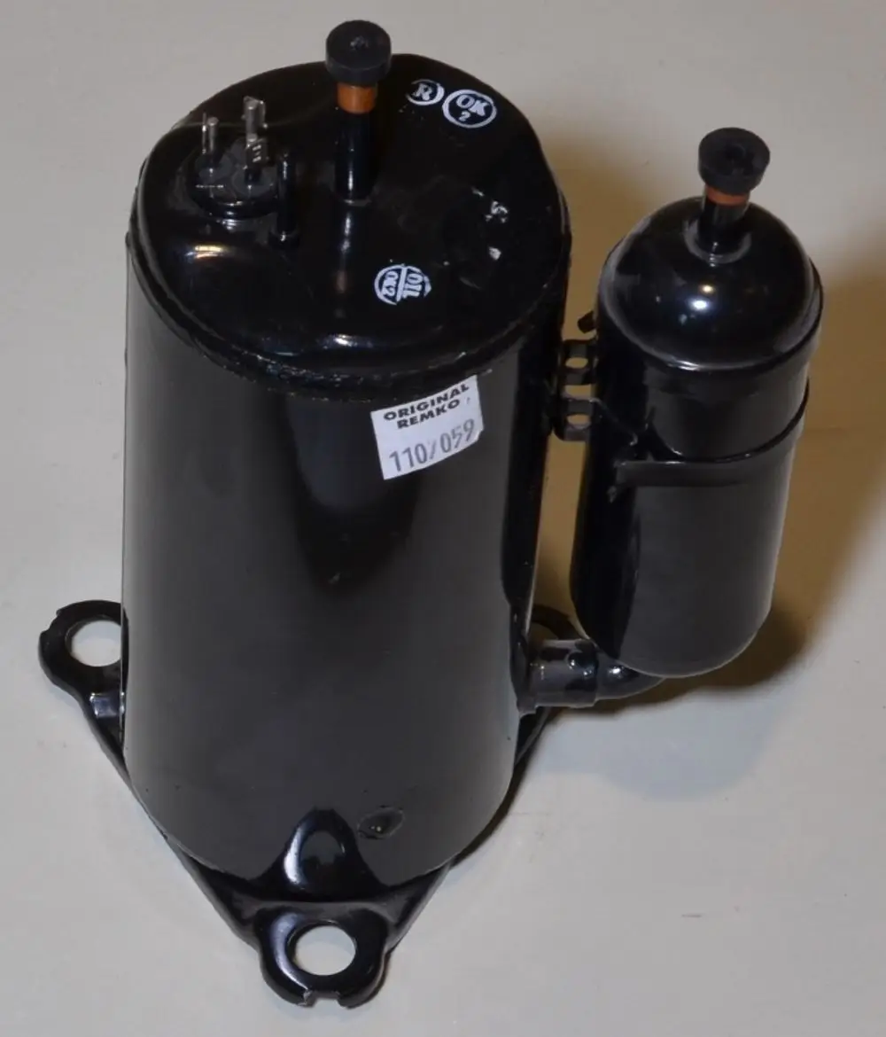 Schwarzer Kompressor mit zwei Anschlüssen, der die Marke Remko zeigt. Der größere Zylinder hat eine halbrunde Basis und ist an einem kleineren Zylinder befestigt.