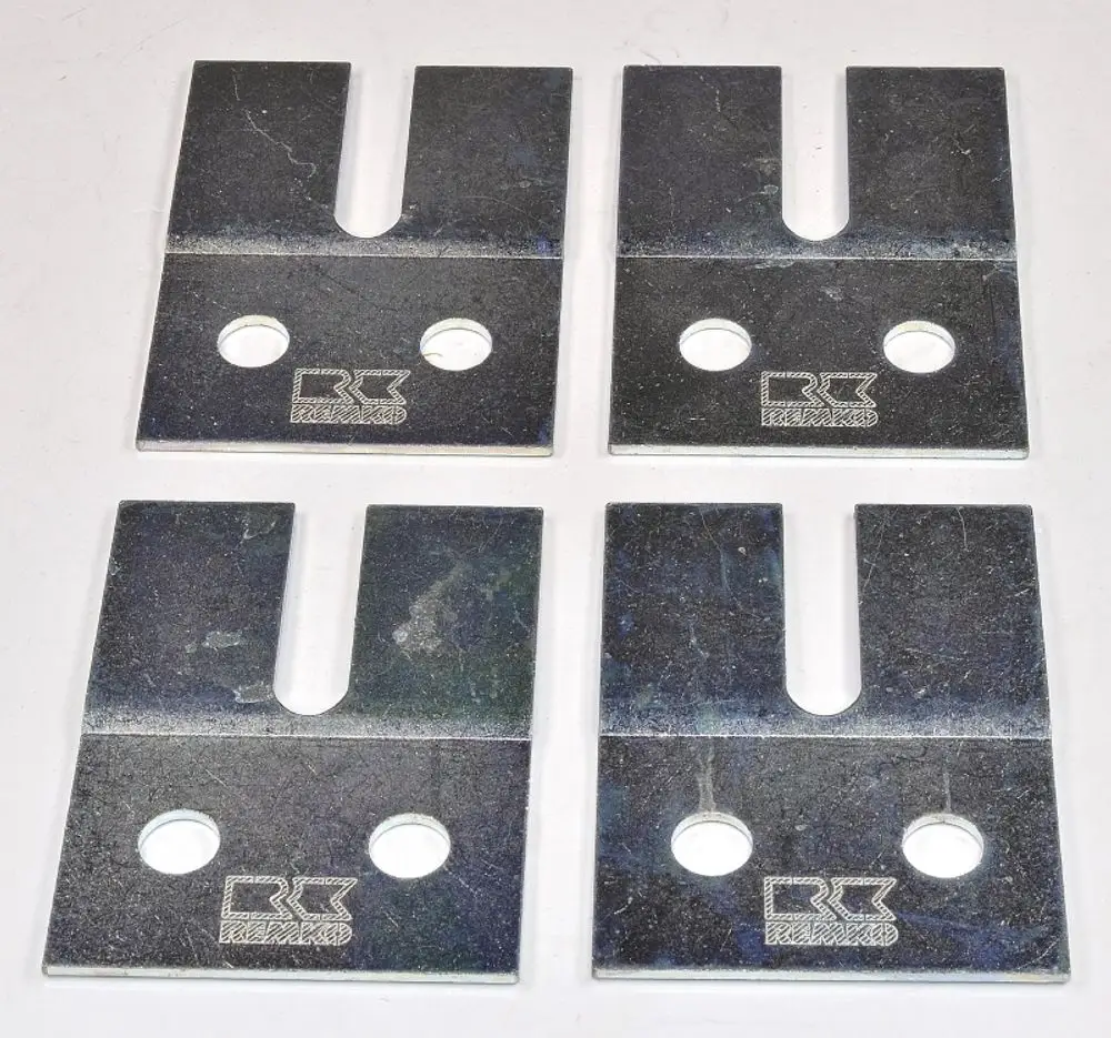 Vier metallene Flachstahlplatten mit zwei Löchern und einer Aussparung, markiert mit dem Logo von Remko, auf heller Unterlage angeordnet.