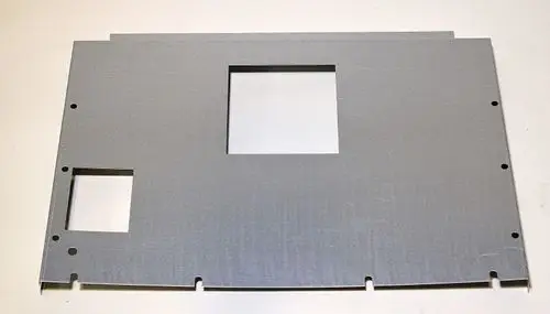 Metallplatte mit zwei Ausschnitten und mehreren Löchern zum Befestigen, möglicherweise Teil eines Geräts von Remko. Die Oberfläche zeigt eine glatte, silberne Verarbeitung.