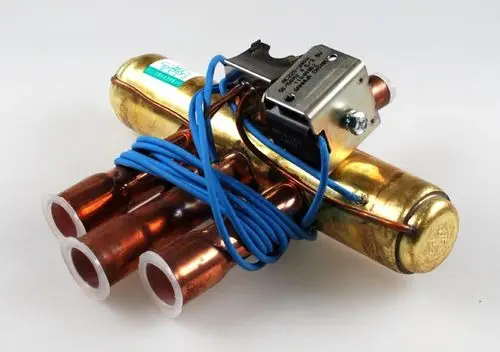 Umkehrventil von Remko, bestehend aus einem metallischen Gehäuse mit mehreren Kupferrohren und Anschlusskabeln. Konstruktion für hydraulische Anwendungen sichtbar.