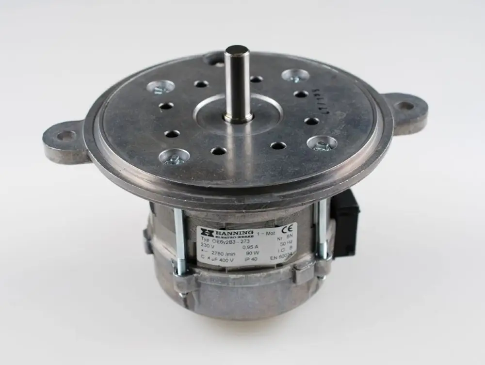 Brennermotor von Remko mit runder Gehäuseform, zentralem Antriebsstift und mehreren Befestigungslöchern auf einer Metallfläche. Anschluss- und Typeninformationen sichtbar.