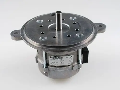 Brennermotor von Remko mit runder Gehäuseform, zentralem Antriebsstift und mehreren Befestigungslöchern auf einer Metallfläche. Anschluss- und Typeninformationen sichtbar.