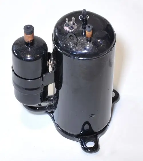 Schwarzer Kompressor mit zwei angeschlossenen Röhren und elektrischen Anschlüssen. Montagetellern sind sichtbar. Produkt von Remko.