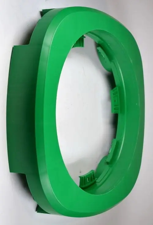 Grüner, ovaler Kunststoffring mit Aussparungen, verwendet als Tragring, möglicherweise für ein Gerät von Remko. Er liegt flach auf einem neutralen Untergrund.