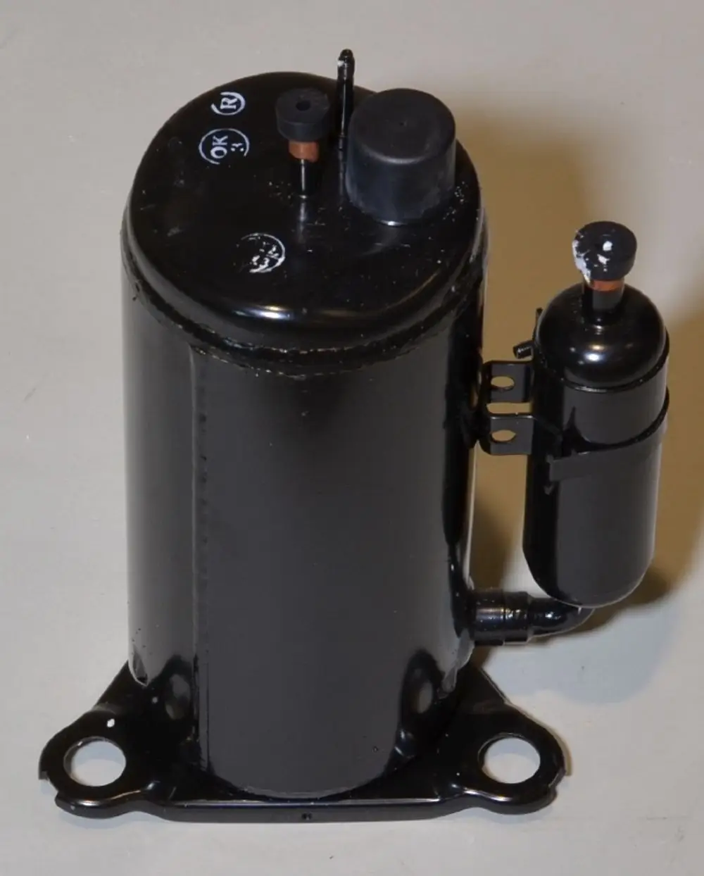 Schwarzer Kompressor mit zwei Anschlussöffnungen, einer größeren Oberseite und einem seitlichen Zylinder. Produkt von Remko mit typischer Konstruktion für Kühlanwendungen.