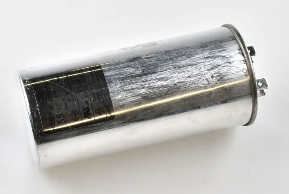 Kondensator von Remko, sichtlich abgenutzt und metallisch glänzend, mit zwei benutzten Anschlussklemmen an einem Ende. Die Beschriftung ist teilweise sichtbar.