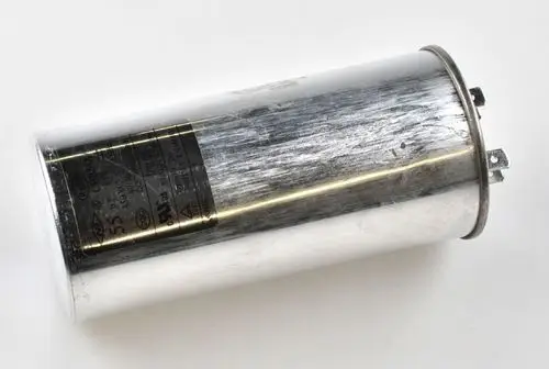 Kondensator von Remko, sichtlich abgenutzt und metallisch glänzend, mit zwei benutzten Anschlussklemmen an einem Ende. Die Beschriftung ist teilweise sichtbar.