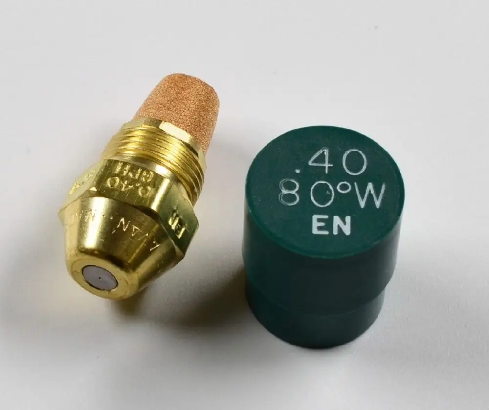 Öldüse in Messing mit einer korkähnlichen Spitze. Dazu ein grünes Zubehörteil mit Beschriftung, möglicherweise von der Marke Remko.