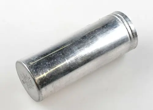 Aluminiumgefertigter Zylinder mit glatter Oberfläche, möglicherweise ein Kondensator, wahrscheinlich von der Marke Remko, auf weißem Hintergrund.