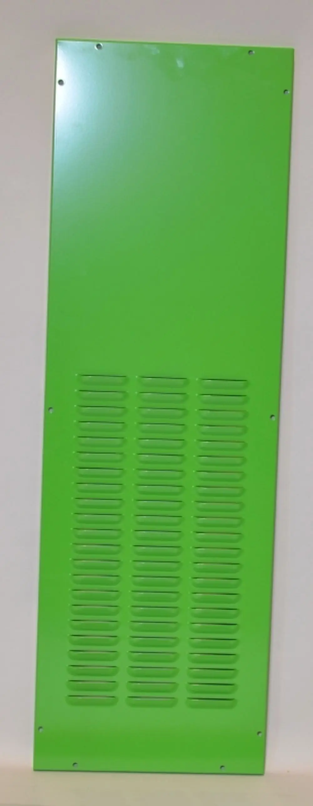 Grünes Verkleidungsblech mit Lüftungsschlitzen, genietet, an einer grauen Wand montiert. Das Produkt stammt von der Marke Remko.