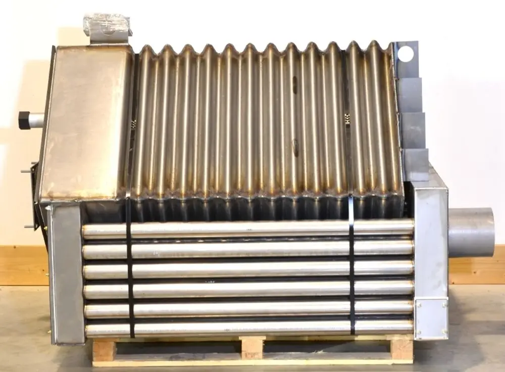 Brennkammer aus Edelstahl mit gerippter Oberfläche, charakteristischem Design und anschlussfertigen Rohren, präsentiert von Remko, auf einem Holzgestell.
