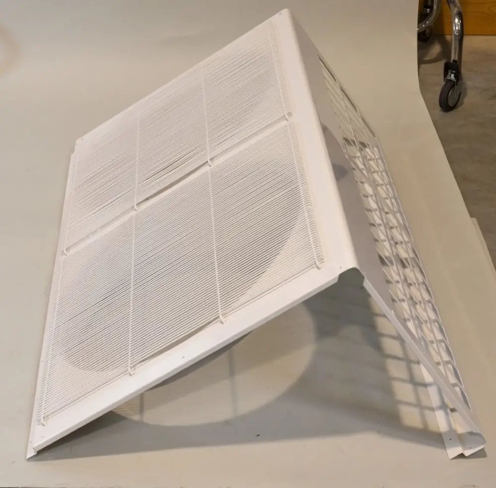 Weißes Ventilatorpaneel mit Gitterstruktur, schräg auf einer Oberfläche platziert. Produkt der Marke Remko, geeignet für Belüftungsanwendungen.