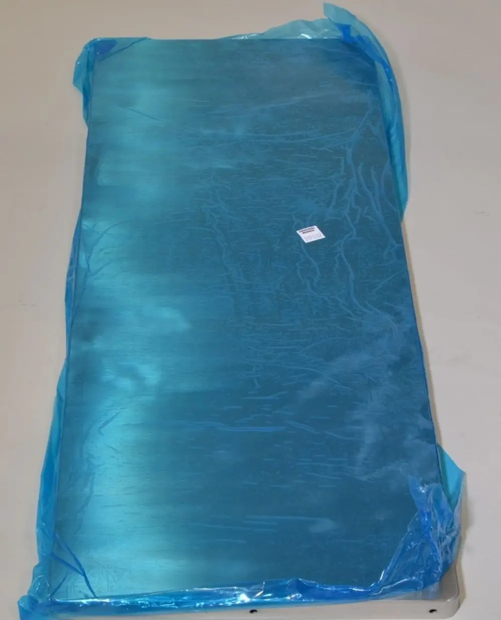 Eingepacktes Metallpaneel in grüner Folie, mit sichtbarem Preisschild. Hersteller ist Remko. Das Produkt hat eine flache und glatte Oberfläche.