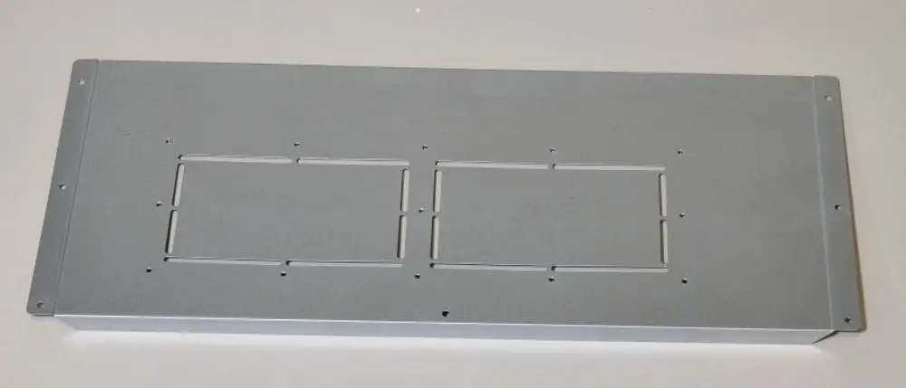 Graue Metallverkleidung mit zwei rechteckigen Ausschnitten und mehreren Befestigungslöchern, wahrscheinlich für eine Remko-Geräteeinheit.