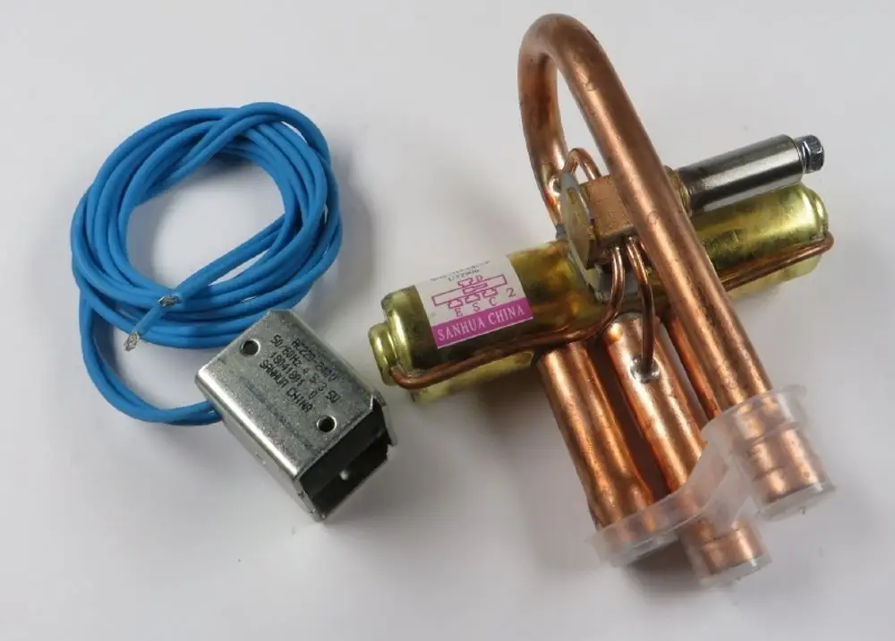 4-Wege-Umkehrventil von Remko, bestehend aus Kupferrohren und einem elektrischen Anschluss, mit einer blauen Kabelader und einem Metallgehäuse.