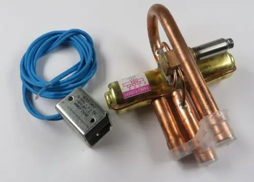 4-Wege-Umkehrventil von Remko, bestehend aus Kupferrohren und einem elektrischen Anschluss, mit einer blauen Kabelader und einem Metallgehäuse.