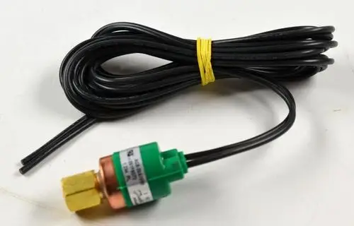 Niederdruckwächter von Remko mit einer grünen und braunen Anschlussmutter sowie zwei schwarzen Kabeln, die zusammengerollt und mit einem gelben Gummiband zusammengehalten sind.