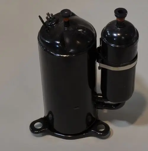 Schwarzer Kompressor von Remko mit zwei zylindrischen Behältern, montiert auf einer Basis. Anschlussleitungen und Ventile sind sichtbar.