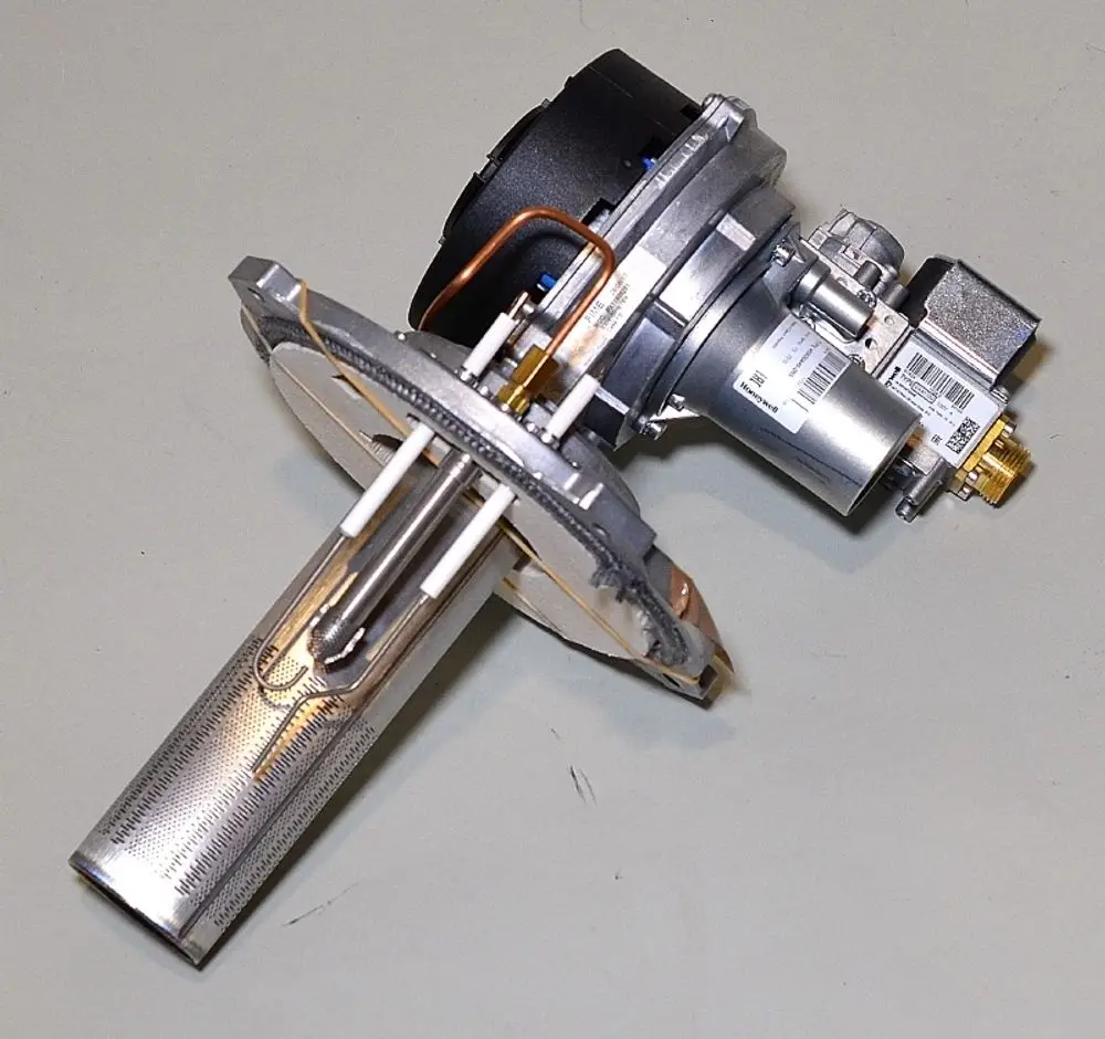 Gasbrenner von Remko mit einem rechteckigen metallischen Gehäuse, einer Zündelektrode und Rohrleitungen. Sichtbare Komponenten für Gaszufuhr und elektrische Anschlüsse.