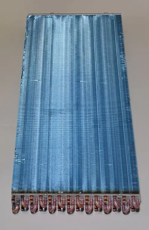 Verdampfer von Remko mit blauer, gerillter Oberfläche und herausstehenden Rohrleitungen an der Unterseite.