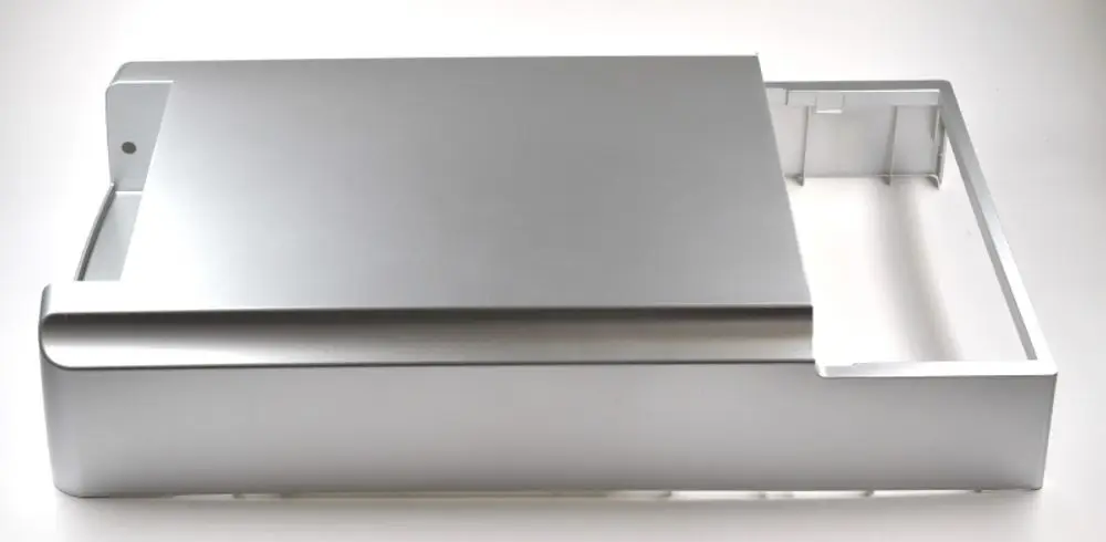 Silberne Metalloberfläche mit abgerundeten Kanten und einer Aussparung. Teil eines Geräts von Remko, möglicherweise eine Abdeckung oder Frontplatte.
