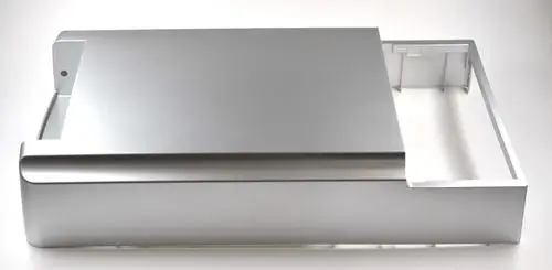 Silberne Metalloberfläche mit abgerundeten Kanten und einer Aussparung. Teil eines Geräts von Remko, möglicherweise eine Abdeckung oder Frontplatte.