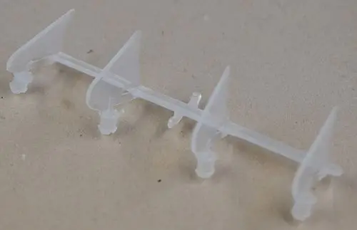 Transparente, vertikale Luftaustrittslamelle von Remko, mit mehreren Auslässen auf einer Plastikkonstruktion, auf hellem Untergrund.