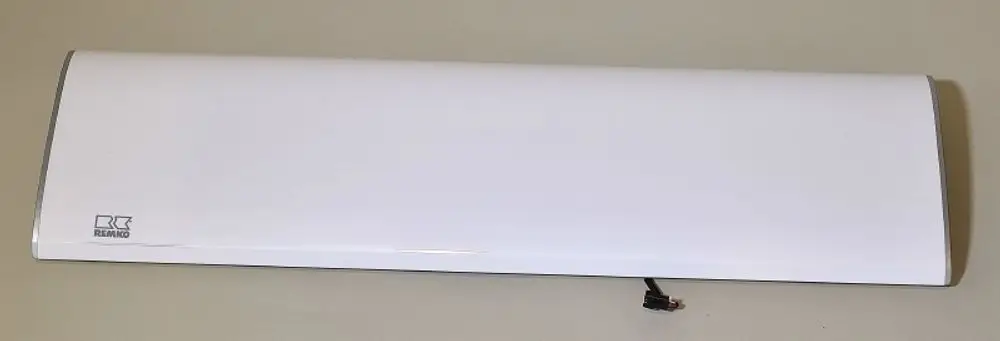 Weißes Gerät von Remko mit flacher, rechteckiger Form und einem Kabel auf der Unterseite, auf grauem Hintergrund.