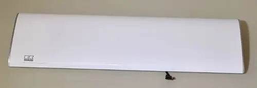 Weißes Gerät von Remko mit flacher, rechteckiger Form und einem Kabel auf der Unterseite, auf grauem Hintergrund.