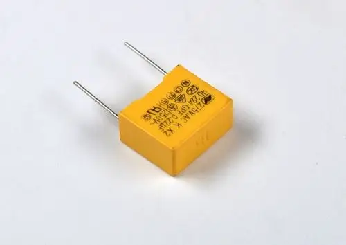 Gelber Kondensator mit zwei Anschlüssen, beschriftet mit technischen Informationen. Produkt von Remko, geeignet für elektronische Anwendungen.