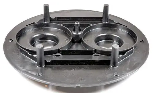 Schwarze, runde Kunststoffplatte mit zwei runden Vertiefungen und mehreren Stiften in der Mitte. Produkt von Remko zur Verwendung im Bereich Turbinentechnik.