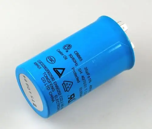 Blauer Kondensator mit Metallanschlüssen, verwendet in Kompressoren, mit Markierungen und technischen Angaben, inklusive des Herstellers Remko.
