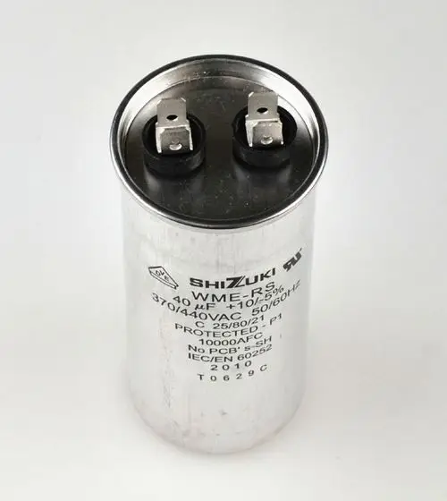 Metallischer Kondensator mit zwei Anschlussklemmen. Auf dem Gehäuse sind technische Daten sowie die Marke Remko zu sehen. Geeignet für Anwendungen in Kompressoren.