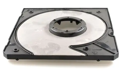 Remko Ventilatorabdeckung auf schwarzem Plastikträger, auf dem Boden liegend. Die Abdeckung hat eine kreisförmige Aussparung in der Mitte und ist flach gebaut.