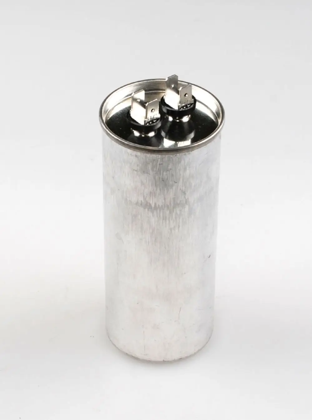 Aluminium-Zylinderkondensator mit zwei Anschlüssen oben, zu sehen vor neutralem Hintergrund. Produkt von Remko, möglicherweise für den Einsatz in Klimaanlagen oder ähnlichen Geräten.