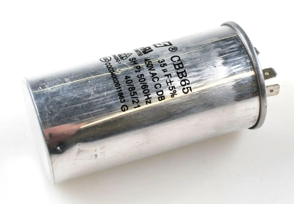 Kondensator der Marke Remko mit metallischer Oberfläche, beschriftet mit technischen Spezifikationen und Anschlüssen. Geeignet für Anwendungen im Kompressorbereich.